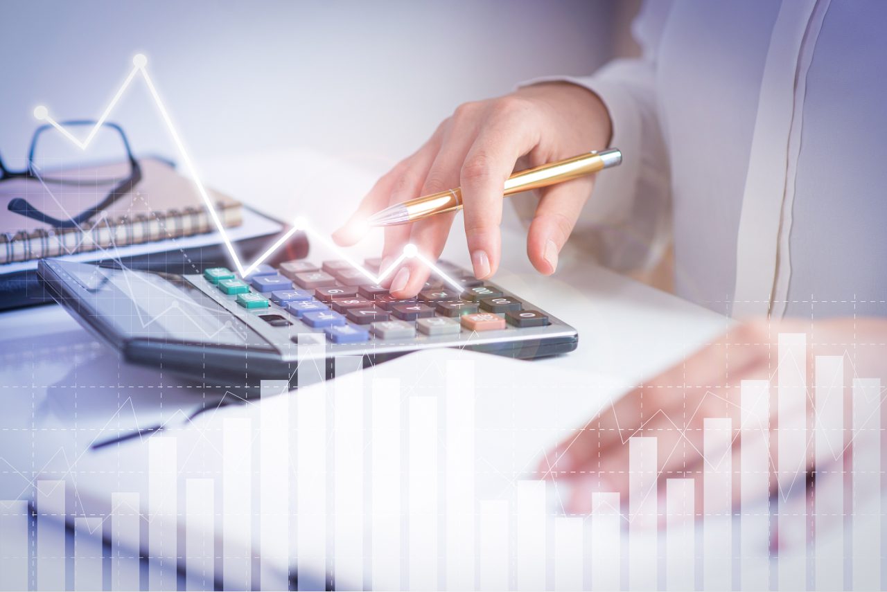 Mulher em escritório está fazendo calculo com calculadora e caderno.