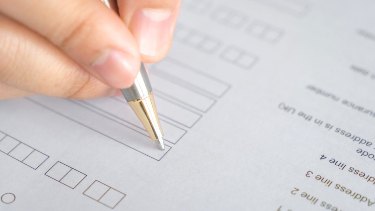 Pessoa respondendo prova com caneta.