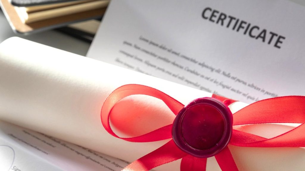 Diploma em canudo e certificado ao fundo.