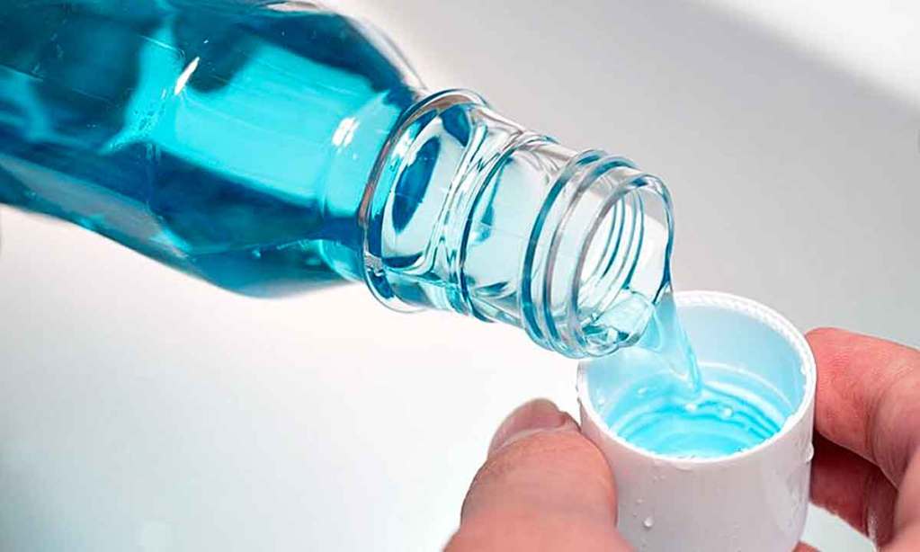 Colocando enxaguante bucal azul na tampinha