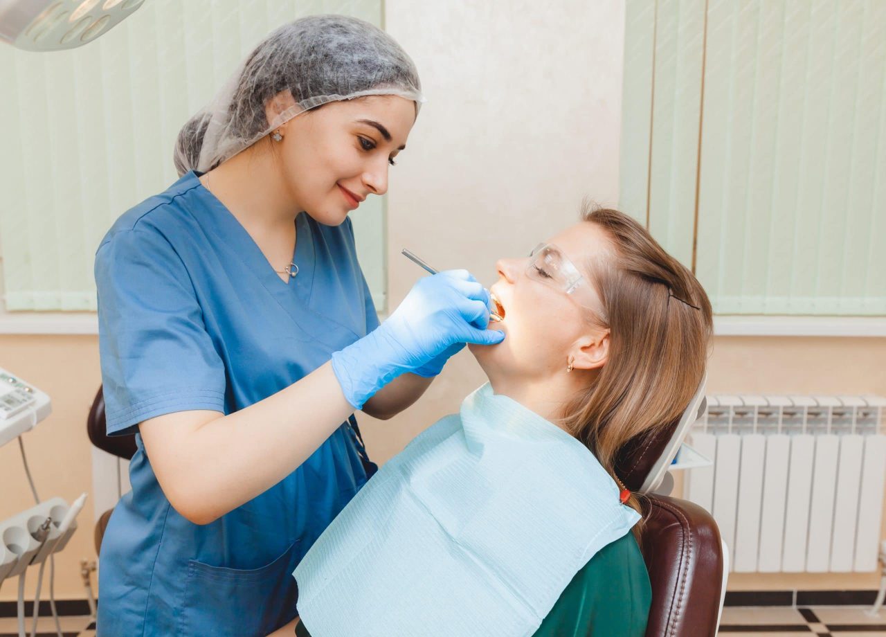 Dentista feliz enquanto atende paciente.