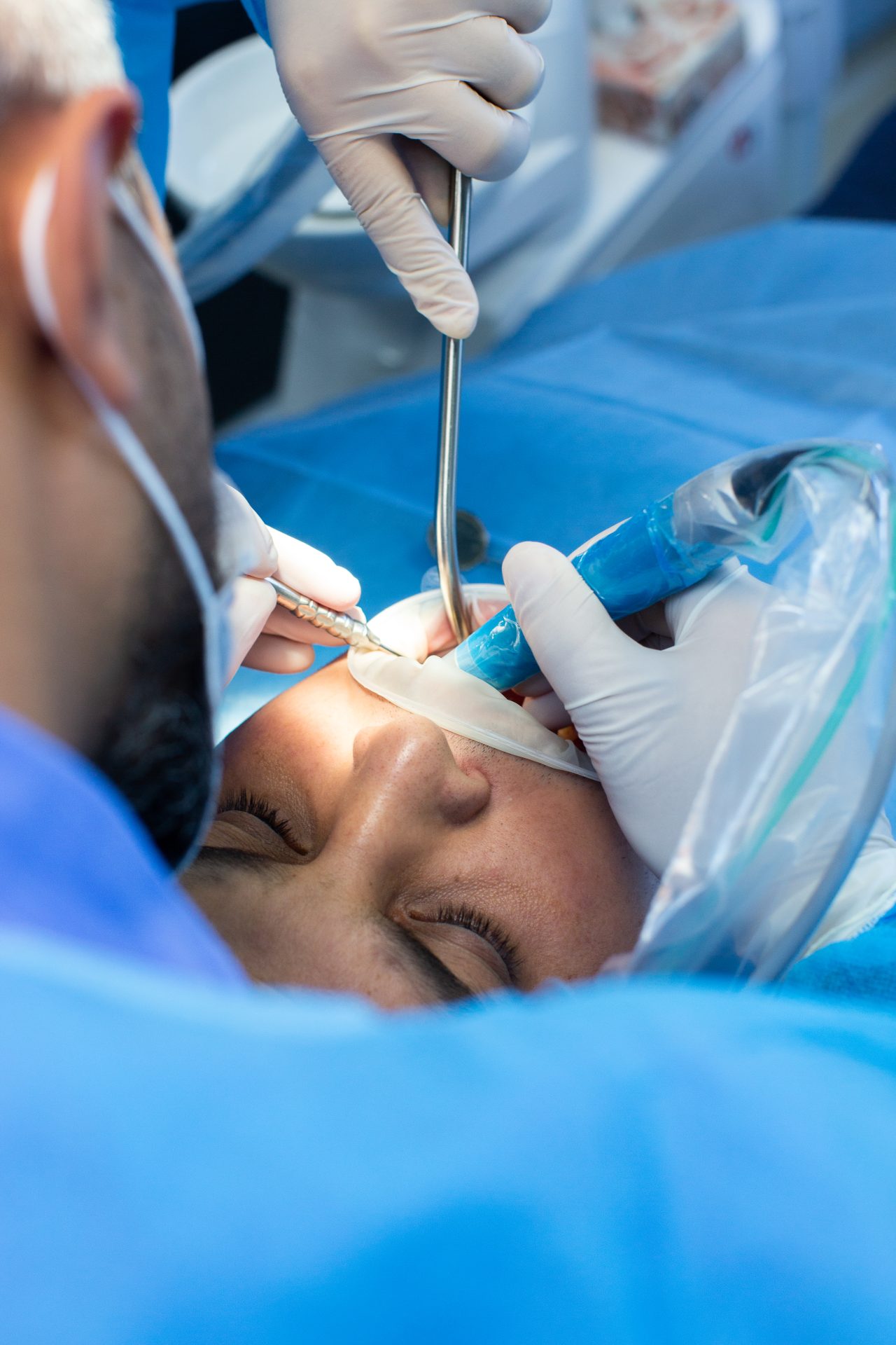 Dentista e seu assistente realizando procedimento paciente.