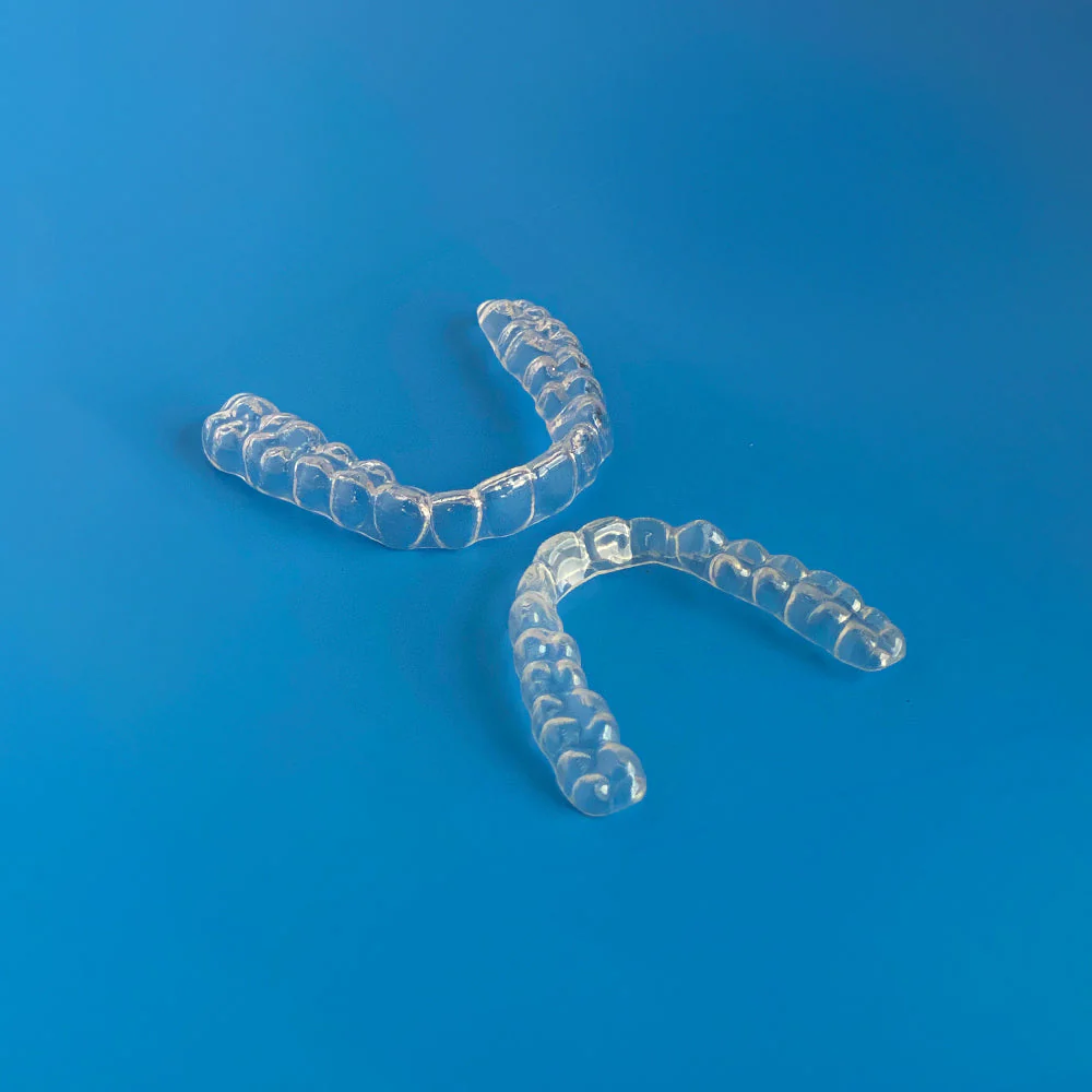 Placas de bruxismo, parte de cima e de baixo, sob um fundo azul.