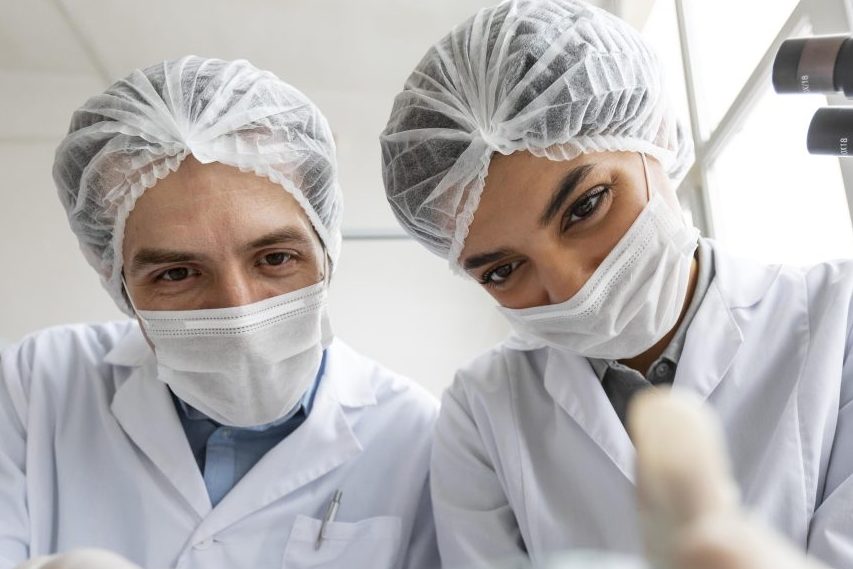 Dentista e assistente estão realizando procedimento em paciente