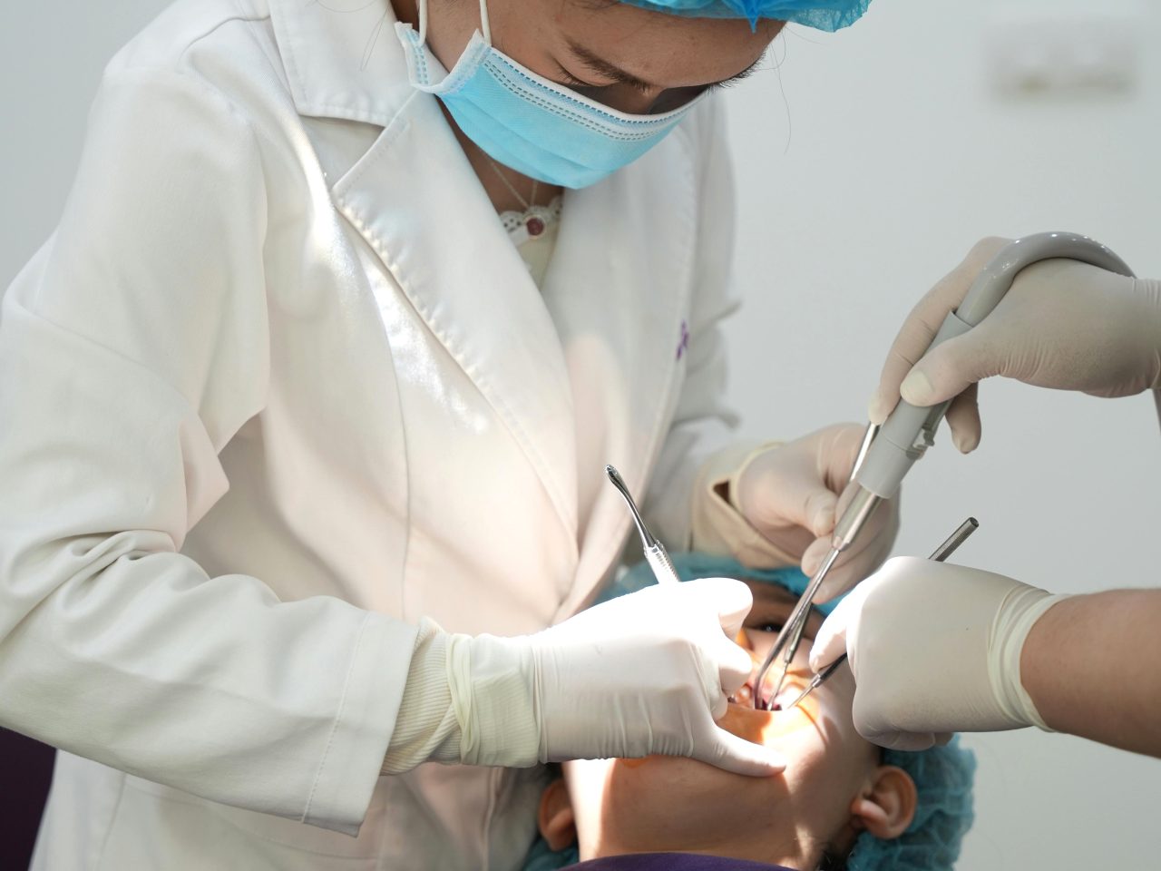 Dentista e assistente realizando cirurgia em paciente.