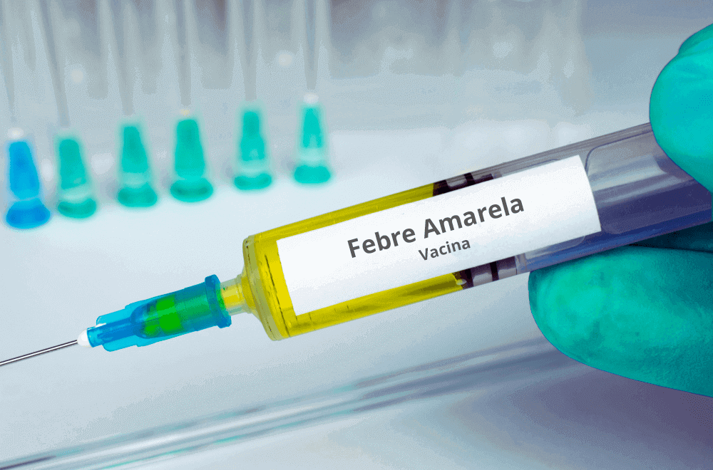 Pessoa de luva verde segurando frasco de Vacina contra febre amarela