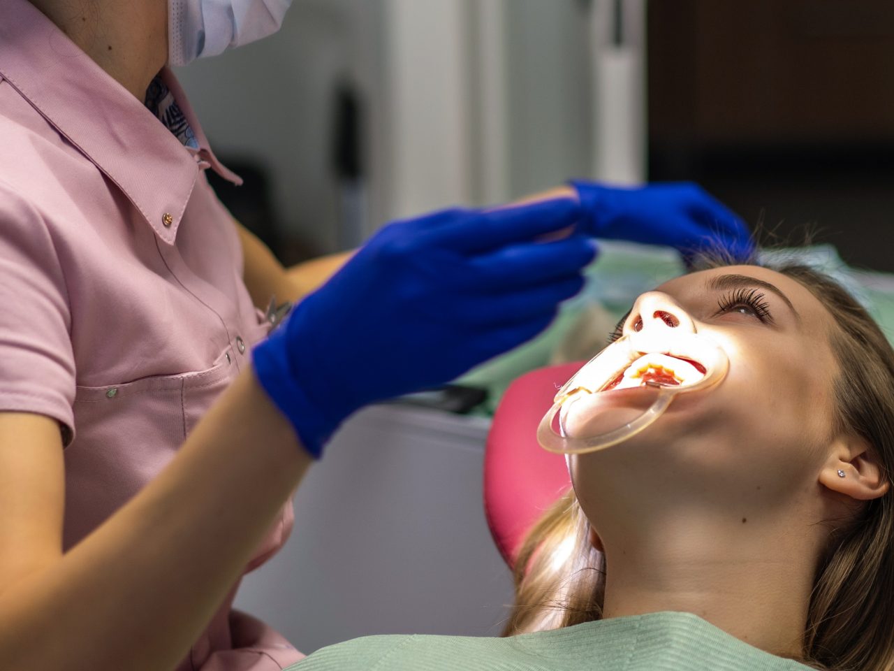 Dentista está realizando tratamento em paciente que está com um afastador de boca.