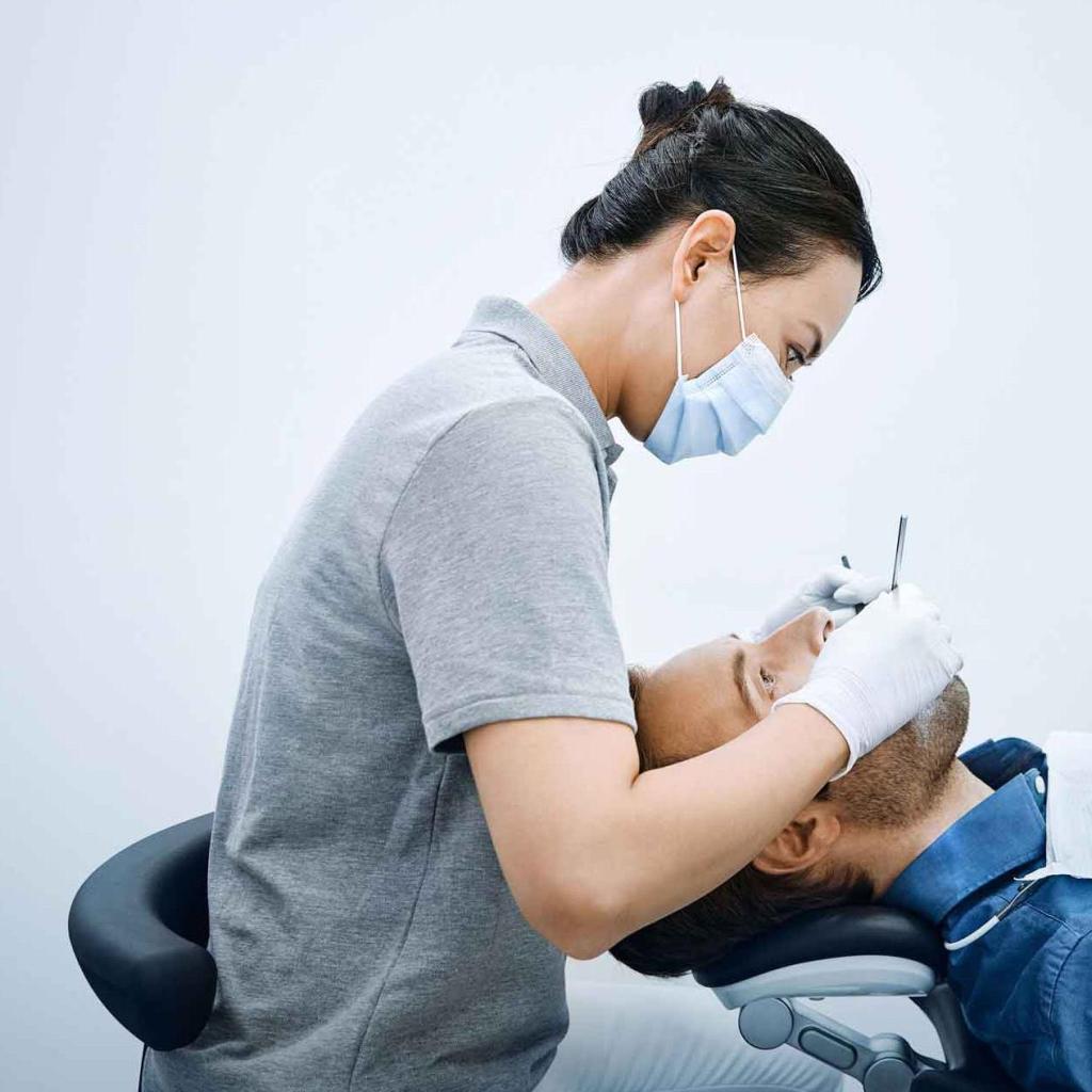 Dentista sentada com a coluna levemente curvada durante atendimento