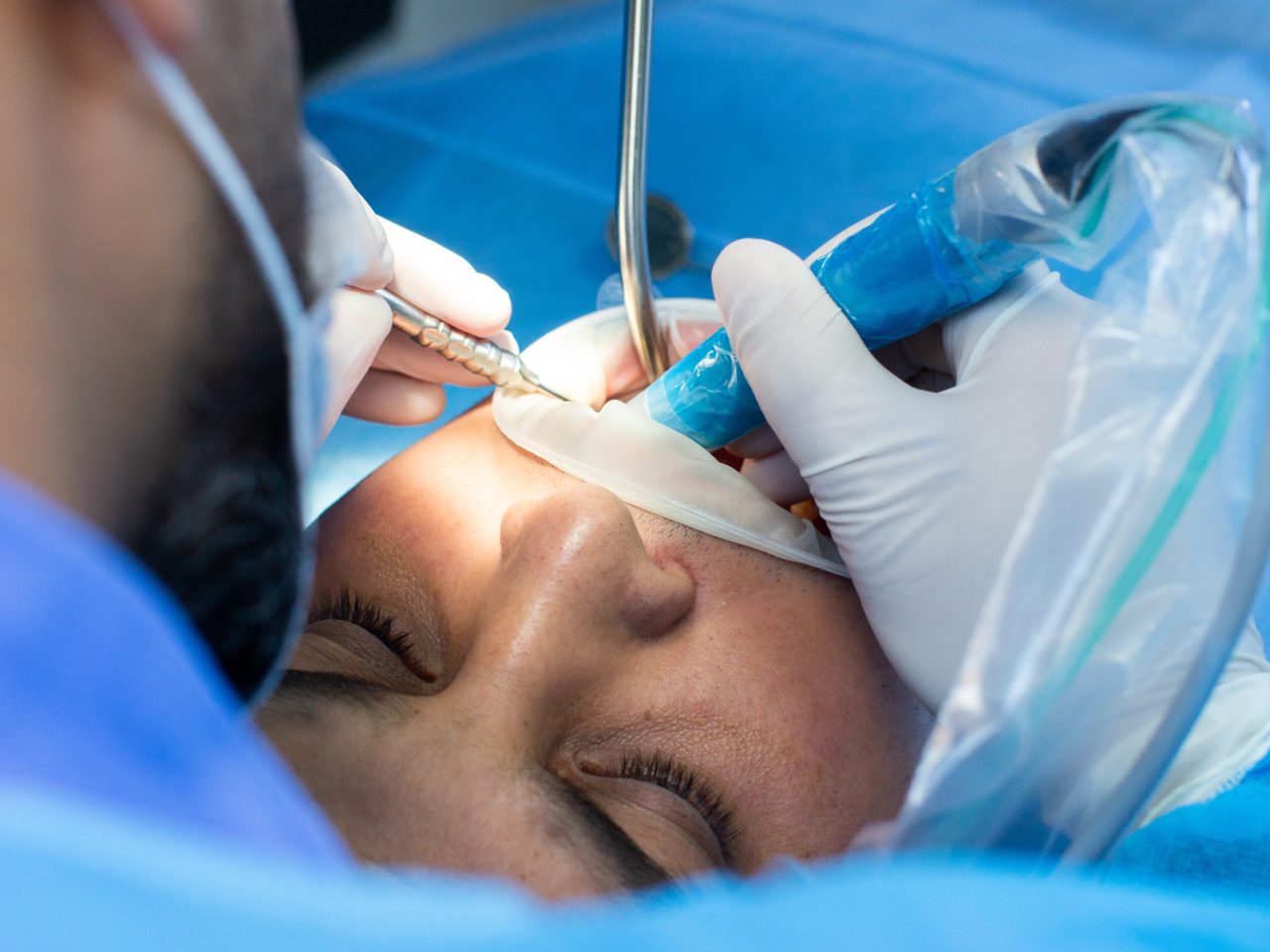 Dentista realizando cirurgia em paciente.