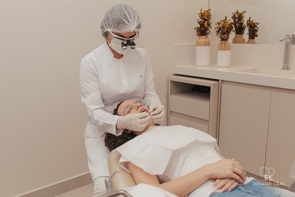 Dentista está sentada atrás de paciente.