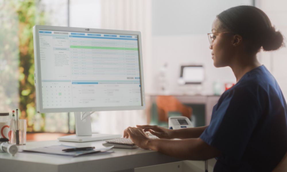 Recepcionista de dentista mexendo em software no computador.