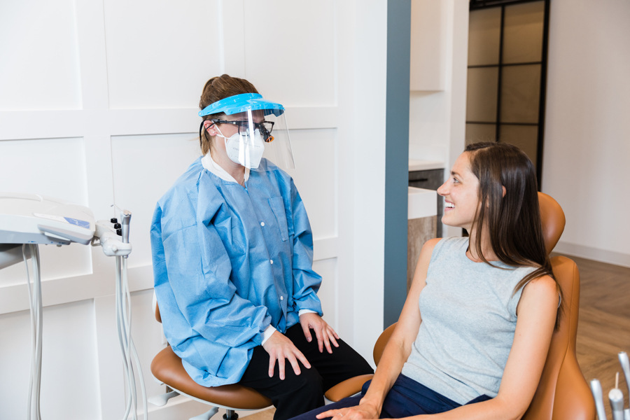 Dentista sentada ao lado de paciente conversando.
