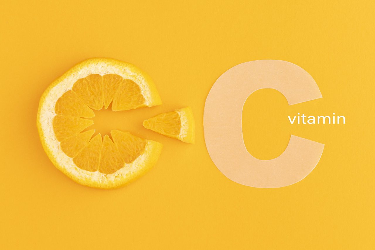 Imagem mostra uma fatia de laranja fatiada e ao lado escrito "vitamin c" imitando o formato da laranja.