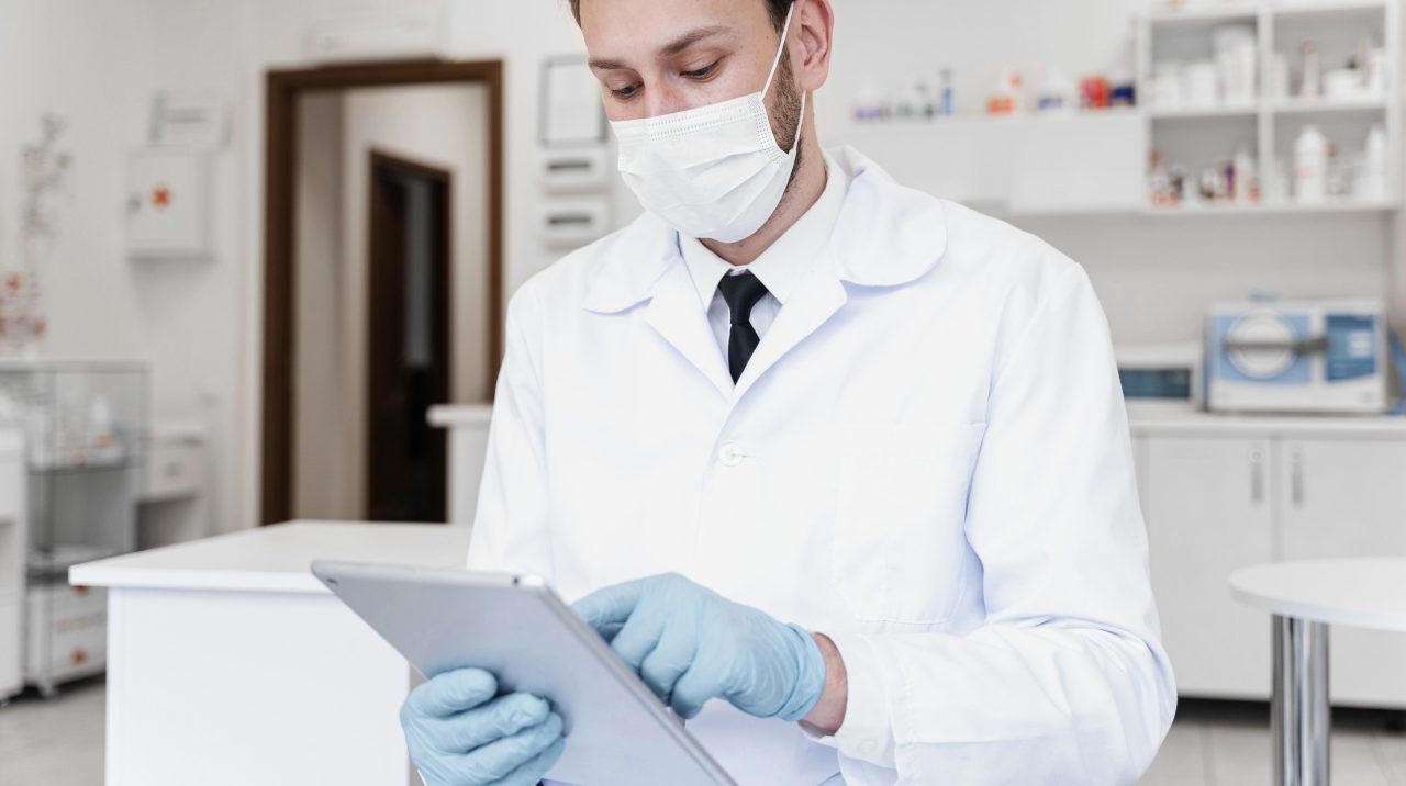 Dentista está sozinho em seu consultório mexendo em tablet.