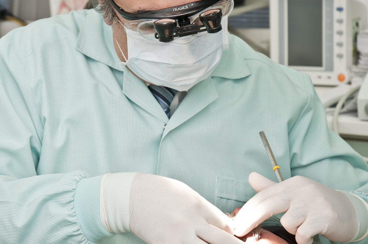 Dentista de cabelo grisalho tratando paciente