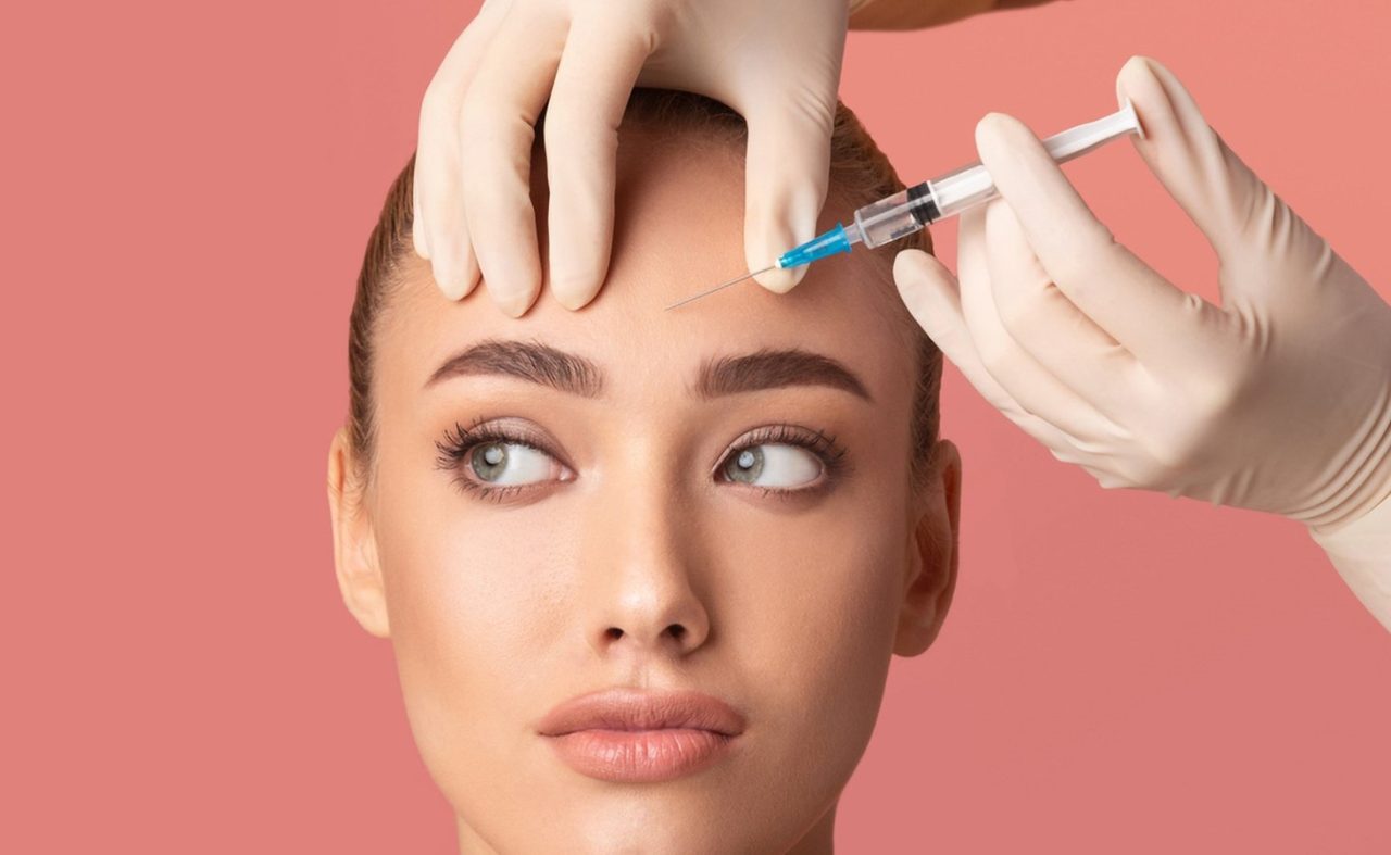 Aplicando botox em testa de jovem moça com seringa.