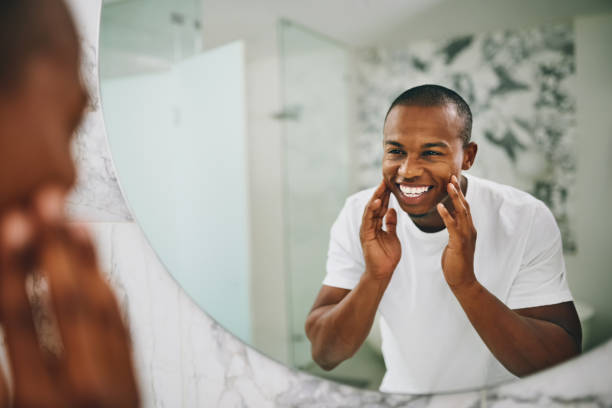 Homem olhando para o espelho e sorrindo, com as mãos nas bochechas.