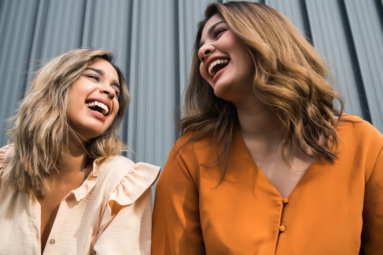 Duas mulheres olhando uma para a outra e rindo juntas.