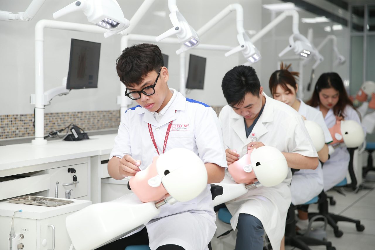 Estudantes de odontologia aprendendo em classe com bonecos.