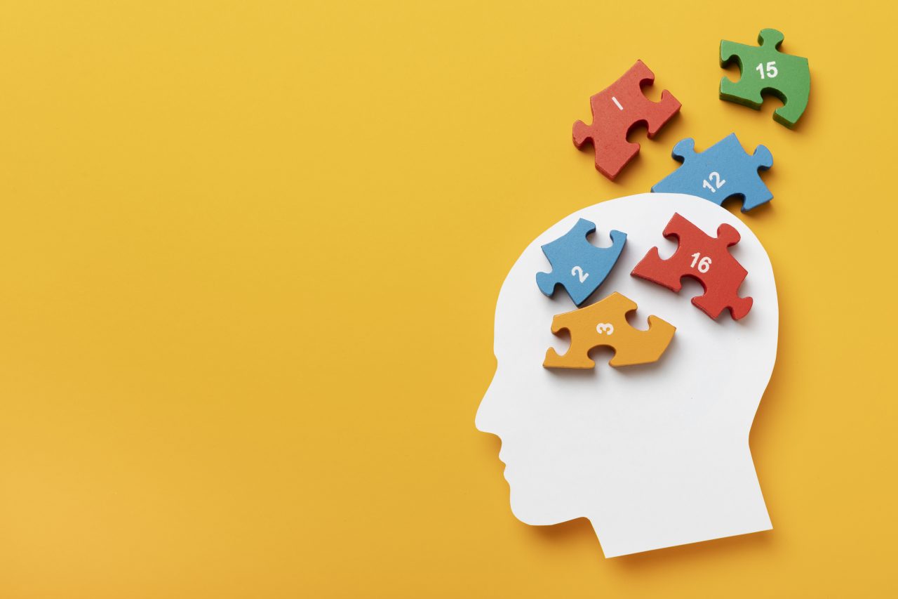 A imagem tem um fundo amarelo. No canto direito tem um desenho de papel em formato de uma cabeça. Na parte do crânio e saindo do desenho tem blocos de montar quebra cabeça numerados.
