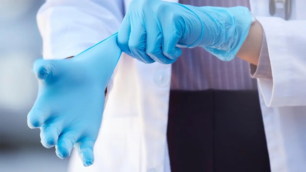 Dentista colocando as luvas descartáveis azuis.