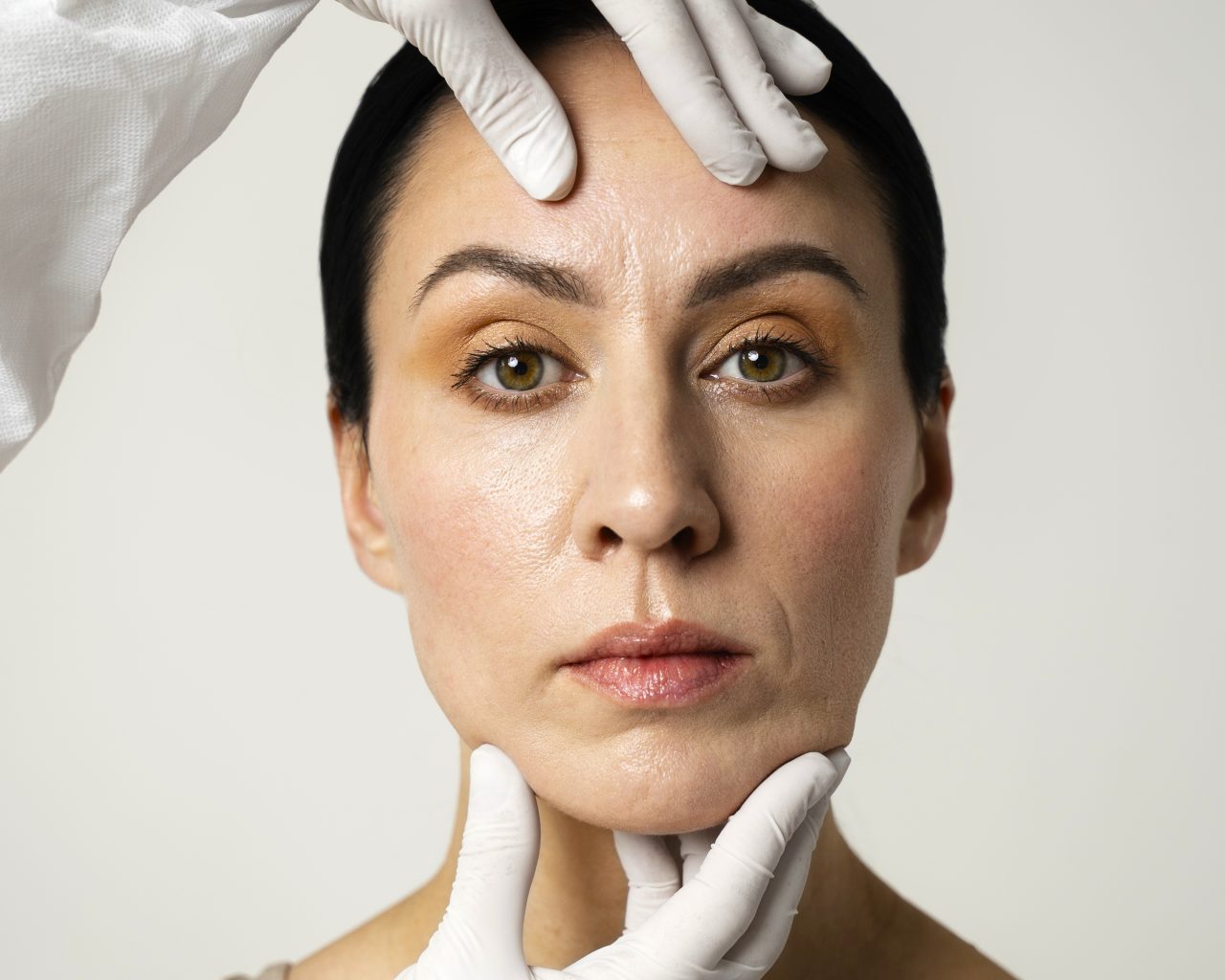 Pessoa usando luva descartável branca está segurando rosto de uma mulher
