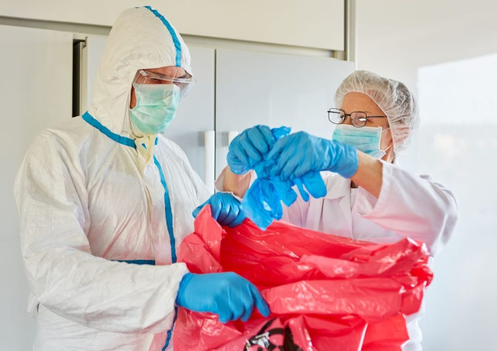Dentistas descartando luvas em saco próprio para resíduos infectantes.