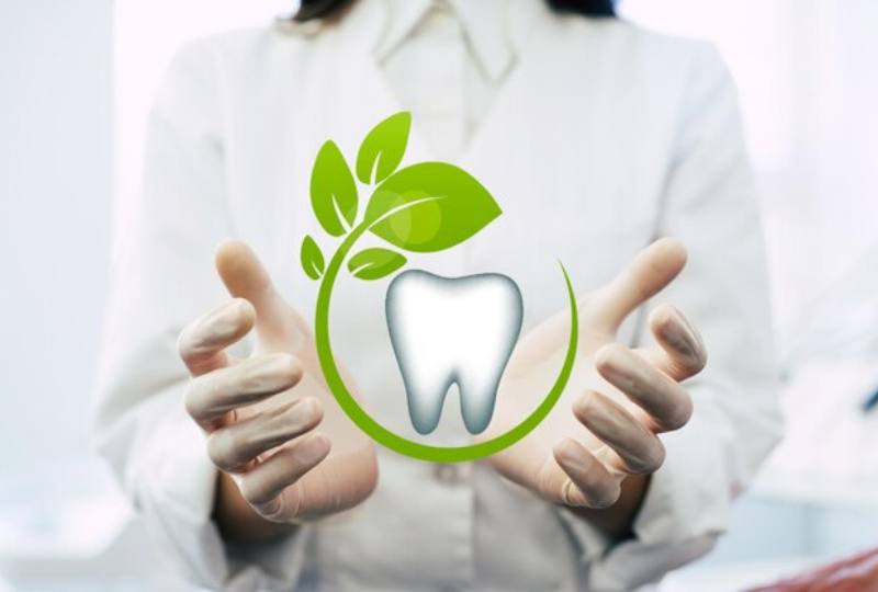 Dentista está com as palmas das mãos em volta de um desenho de um dente com folha representando sustentabilidade na odontologia.