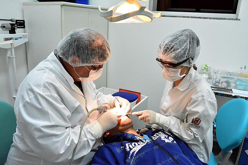 Dentista e sua auxiliar atendendo paicente no SUS.