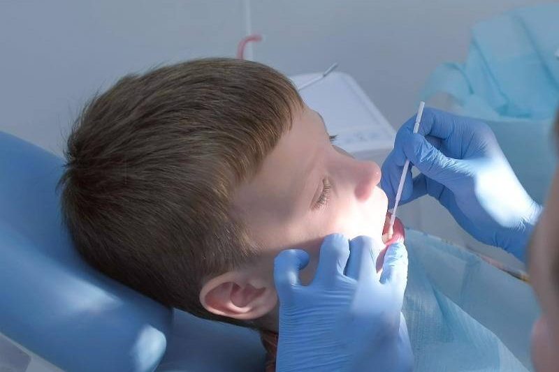 Aplicação de flúor em menino com cotonete.