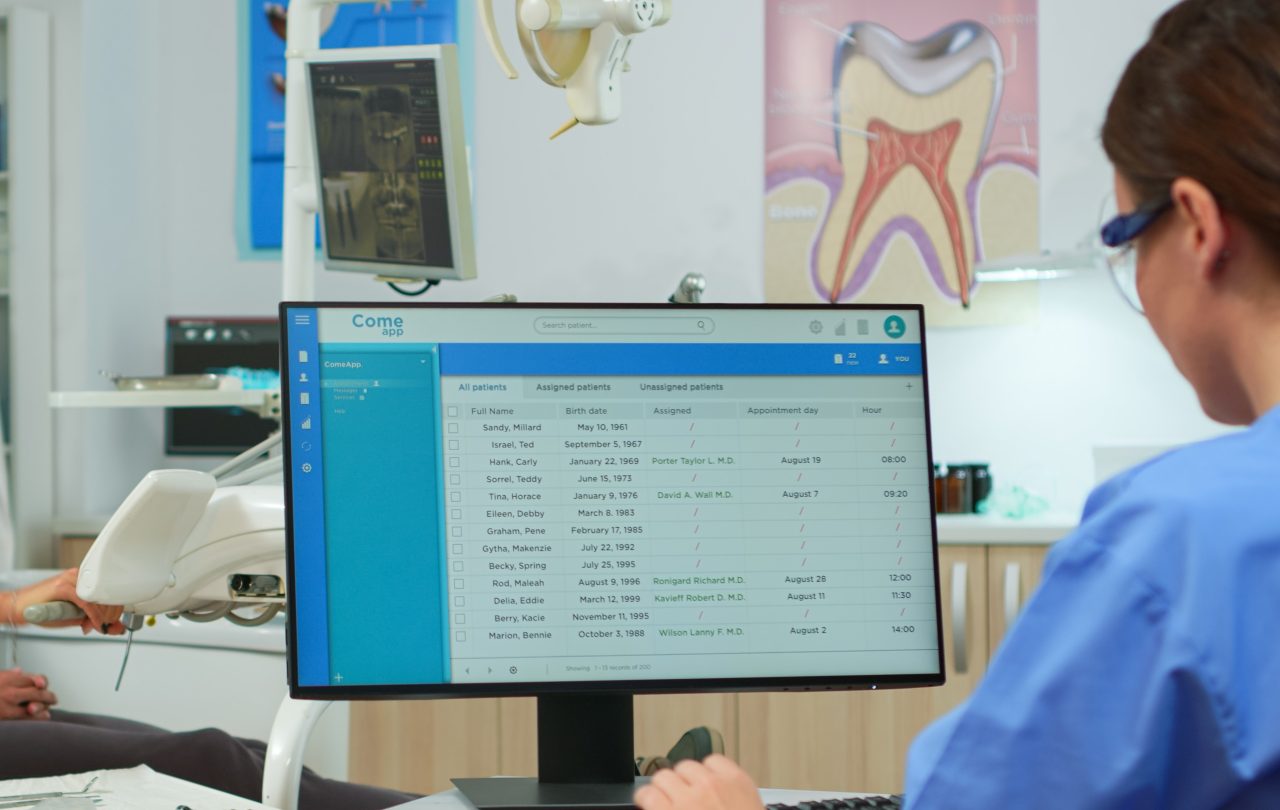 Imagem focada em tela de computador de uma clínica e a secretária digitando