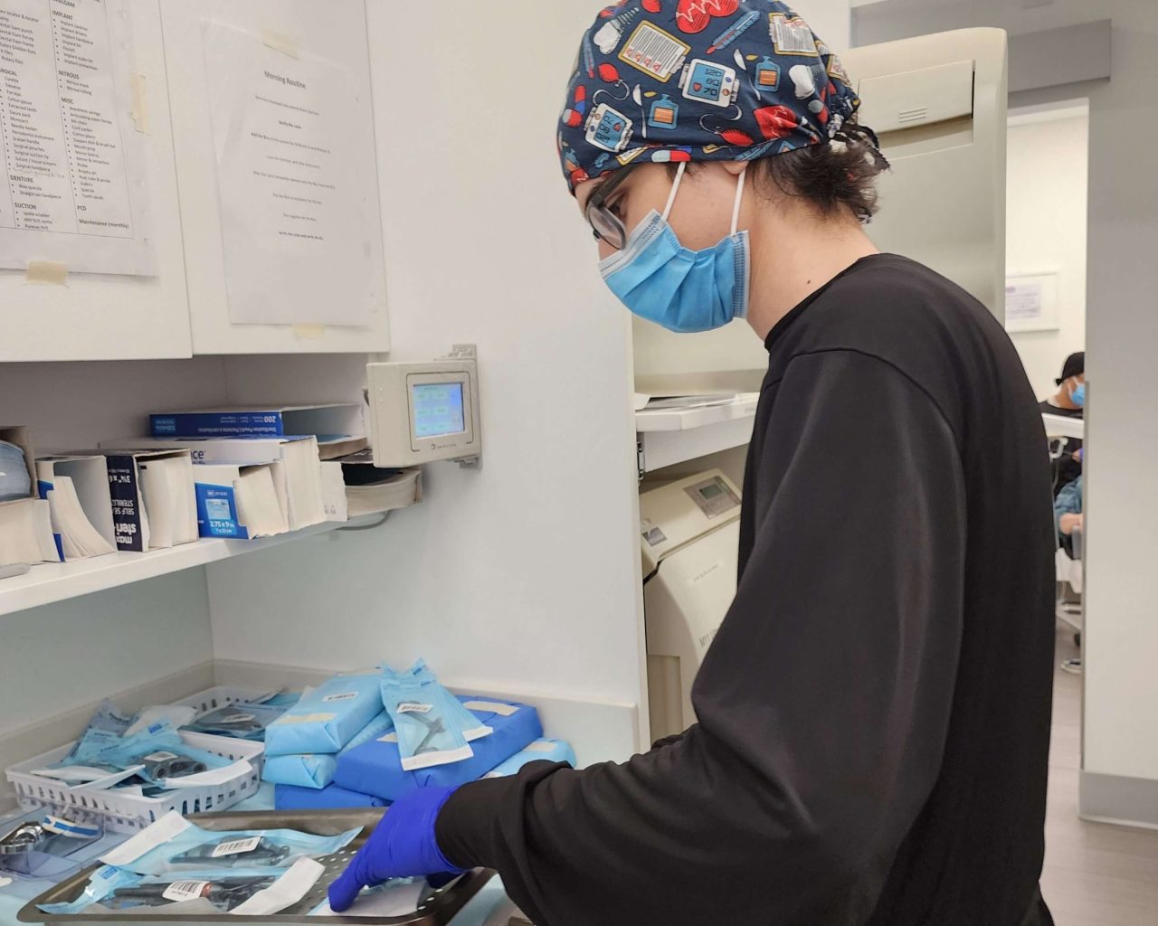 Auxiliar de dentista está arrumando os materiais esterilizados do consultório.