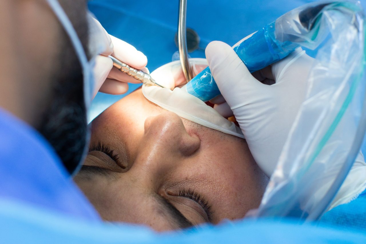 Dentista realizando procedimento em boca de paciente.