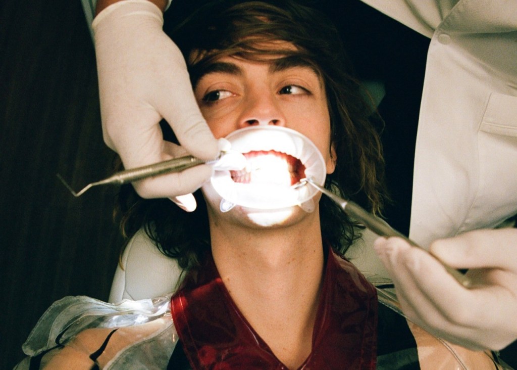 Homem jovem está na cadeira odontológica durante tratamento com isolamento