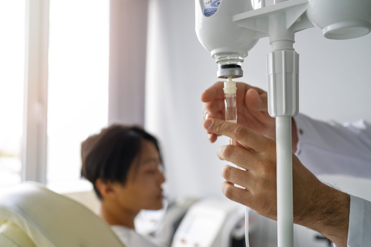 Enfermeiro ajustando medicamento de paciente com leucemia.