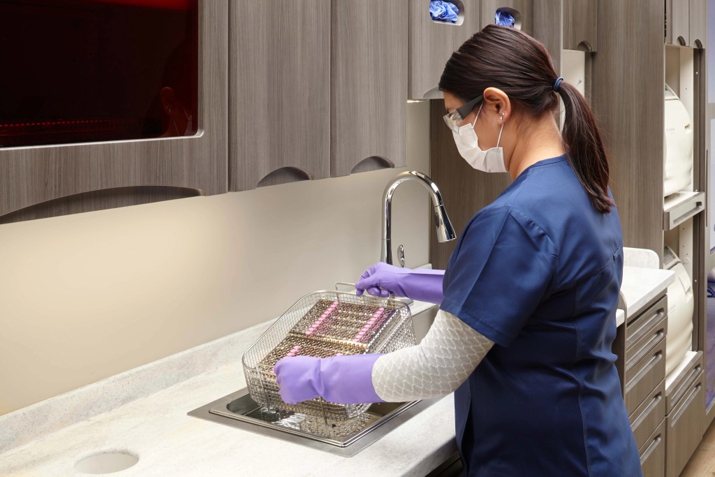 Dentista fazendo manutenção de equipamentos lavando.