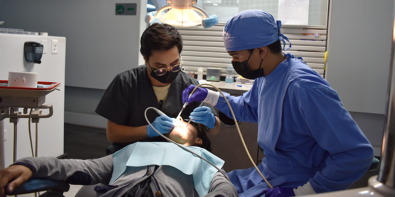 Dentista e seu assistente realizando tratamento dentário em paciente.