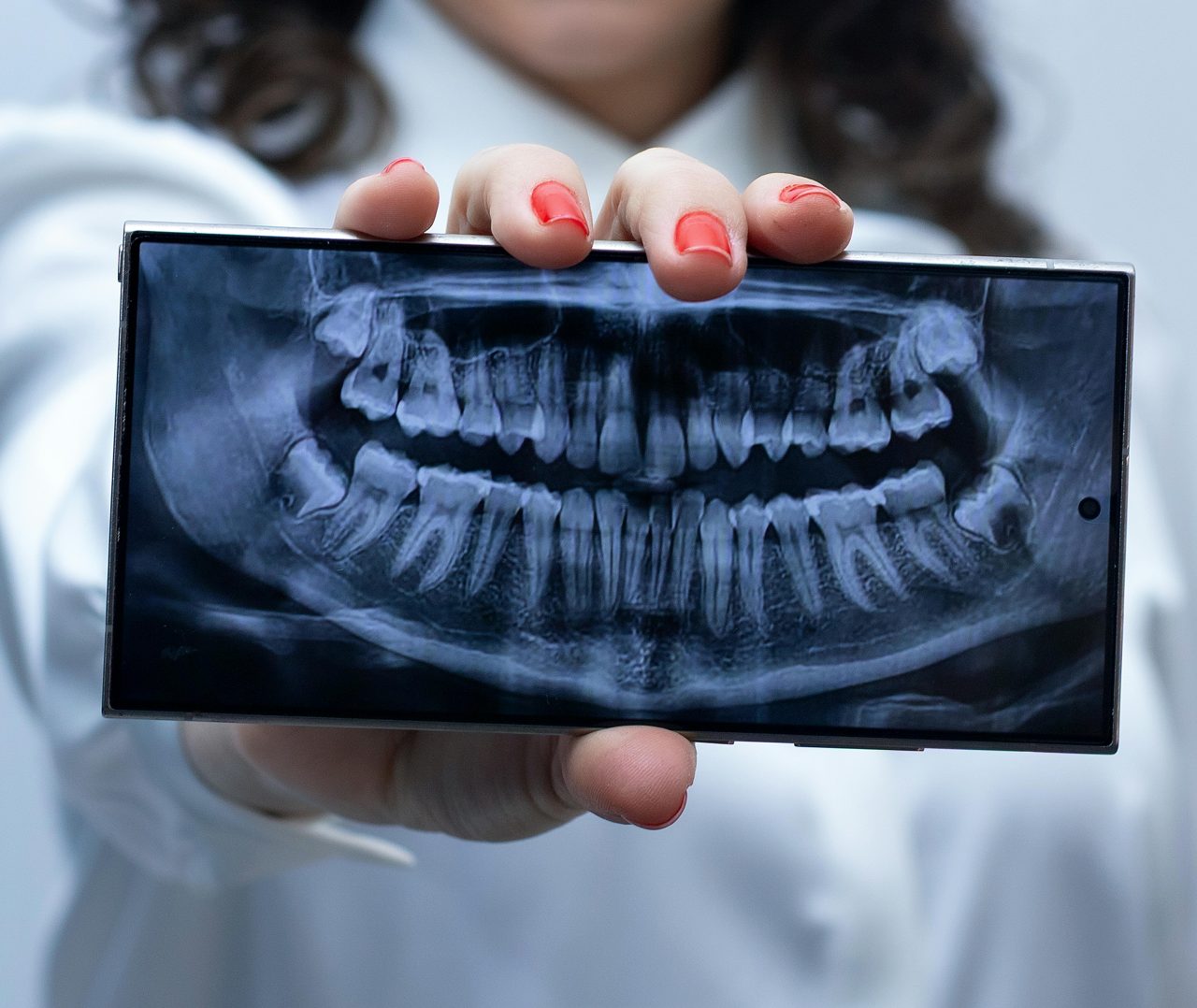 Dentista mostra tela de tablet com radiografia panorâmica aberta.