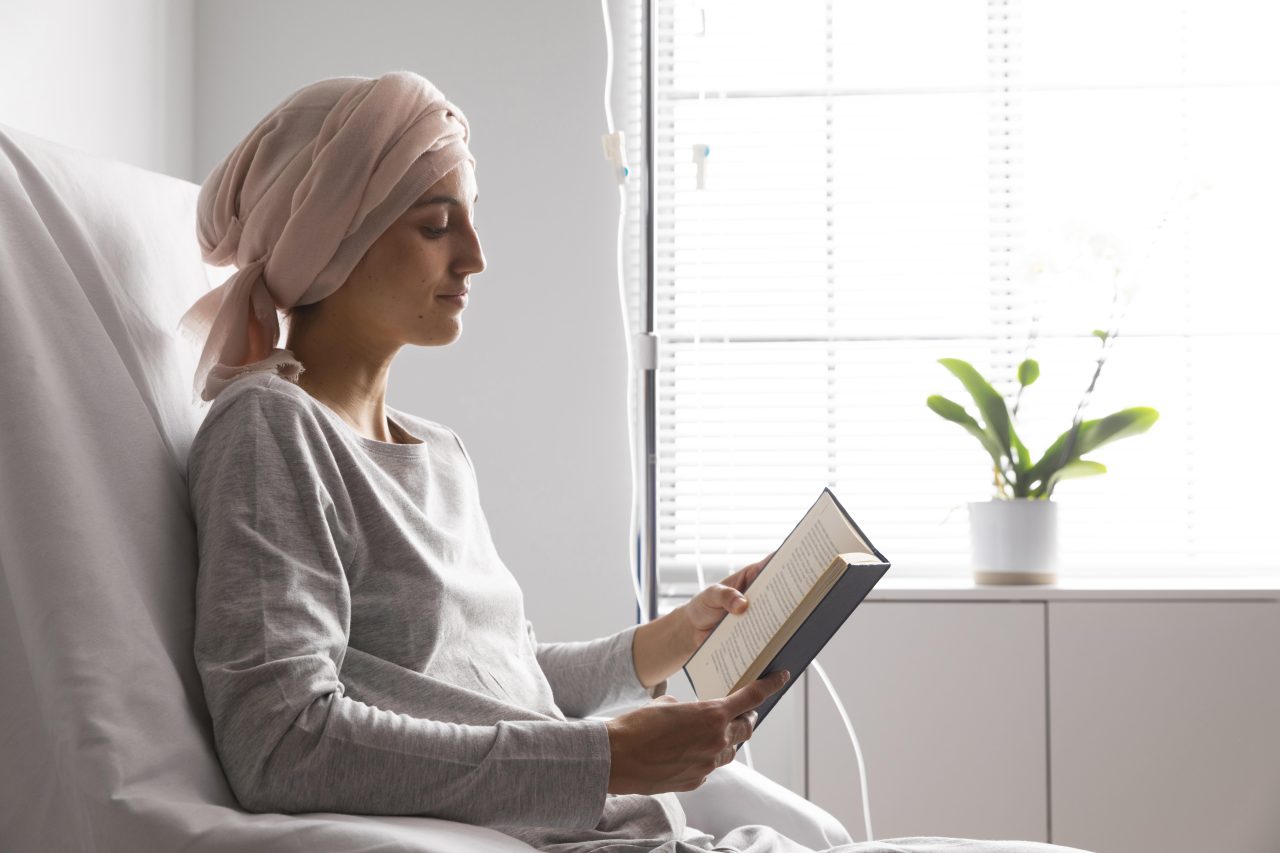 Mulher com leucemia está recebendo tratamento na veia, enquanto lê livro.