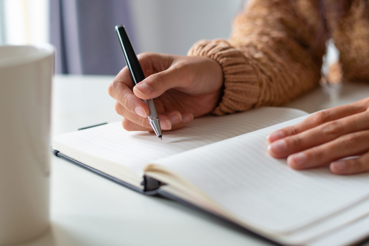 Mulher com caderno em branco, vai começar a escrever.
