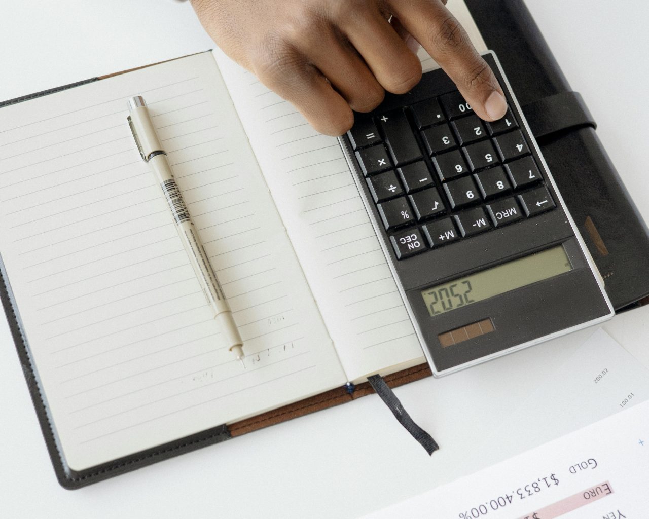 Digitando na calculadora com caderno ao lado.