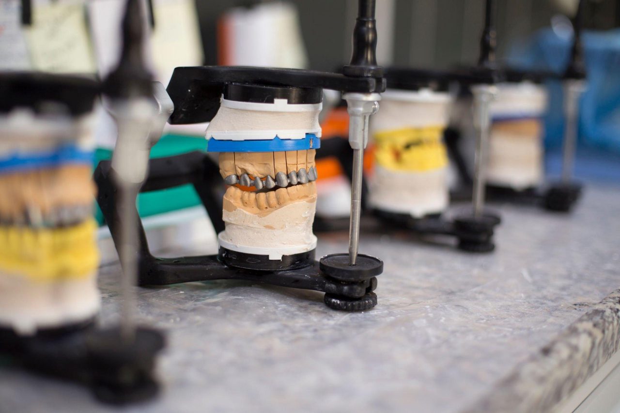 Vários articuladores odontológicos com próteses lado a lado.