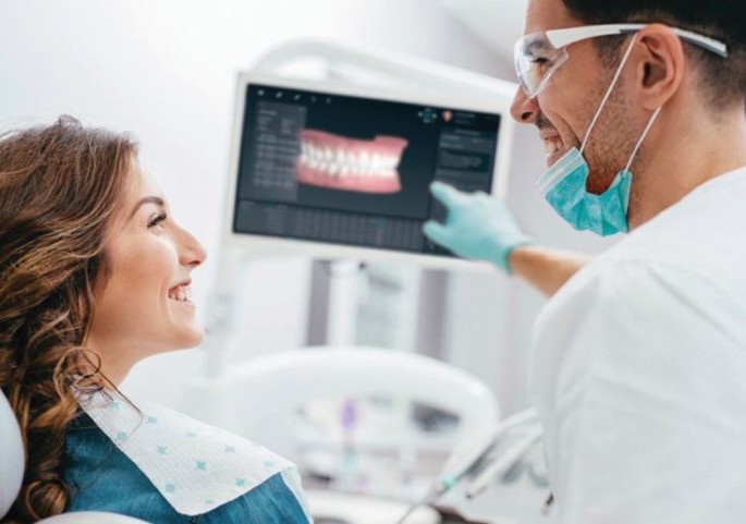 Dentista mostrando planejamento dentário na tela para paciente.