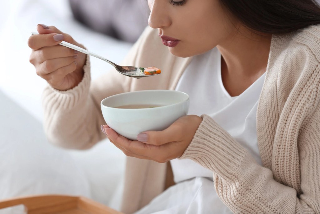 Mulher soprando a sopa para tomar.
