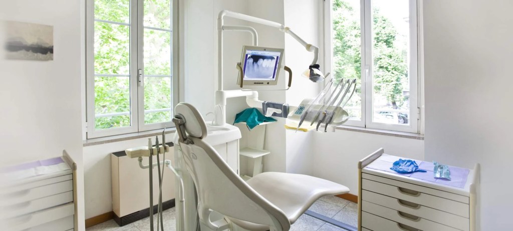 Imagem de consultório odontológico com móveis brancos.