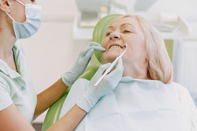 Dentista analisando dentes de paciente idosa.