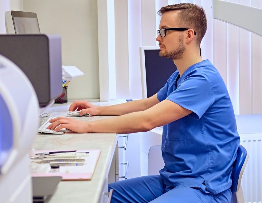 Dentista em sua sala está mexendo em computador