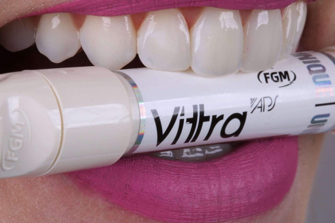 A imagem foca na boca de mulher que está mordendo uma caneta de resina unicromática.