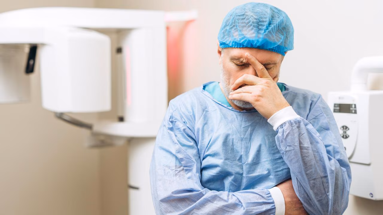 dentista estressado com a cabeça na mão