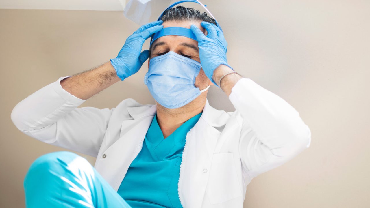 O dentista está estressado com as mãos na cabeça, sentado no chão.